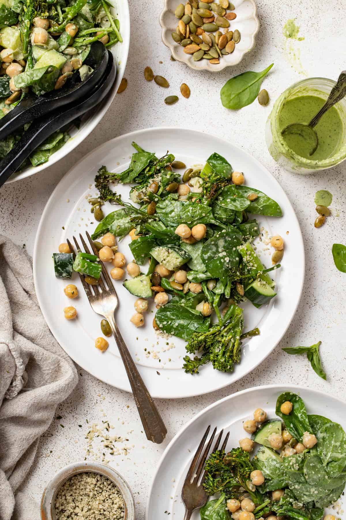 A spinach salad on a plate with a cup of creamy herb dressing next to it.