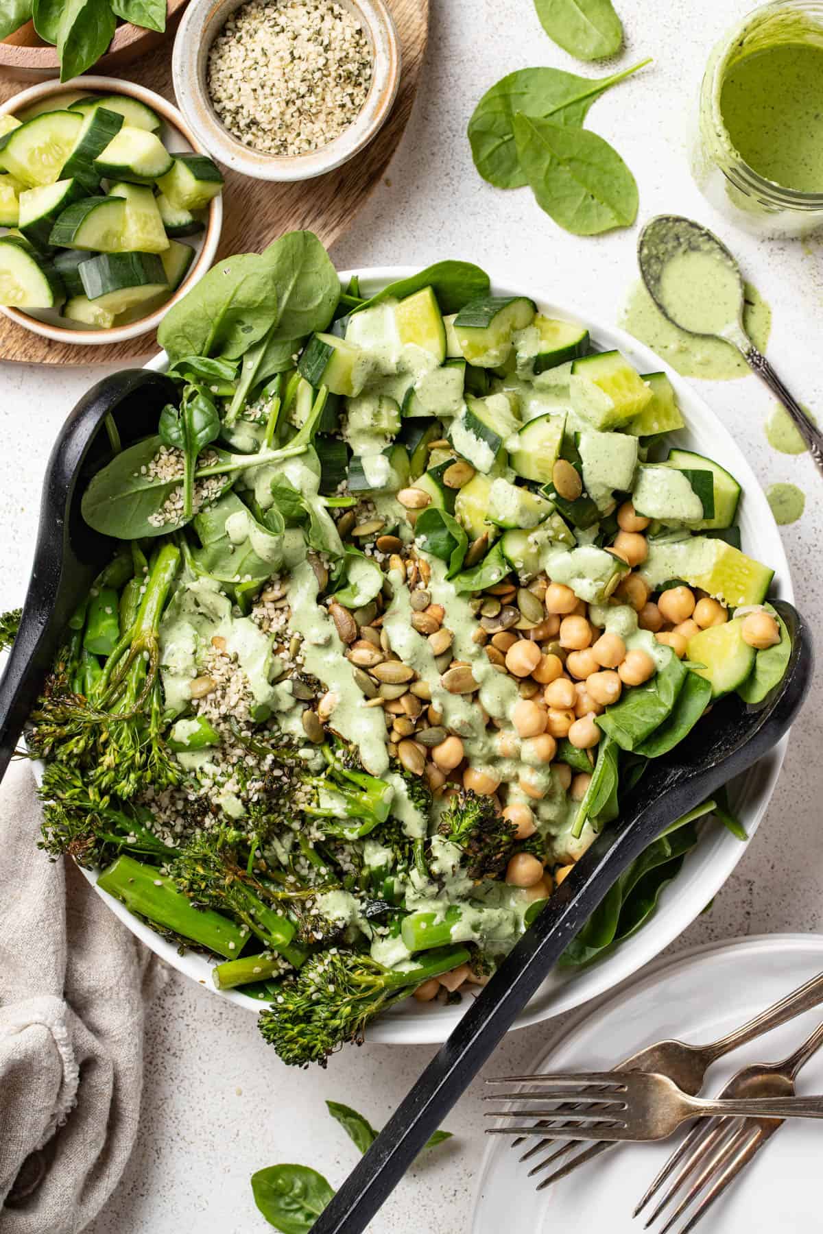 Adding creamy dressing to the spinach salad with a spoon.