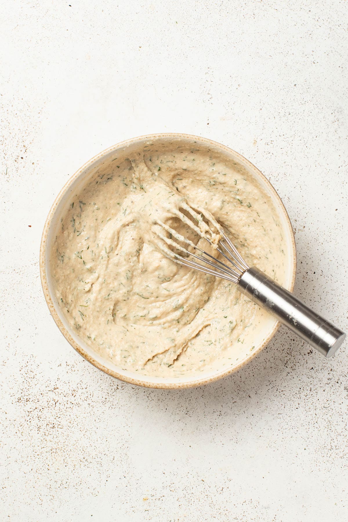 Tahini sauce in a bowl after being whisked till smooth.