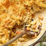 Chicken pot pie noodles on a wood spoon in a cast iron skillet.