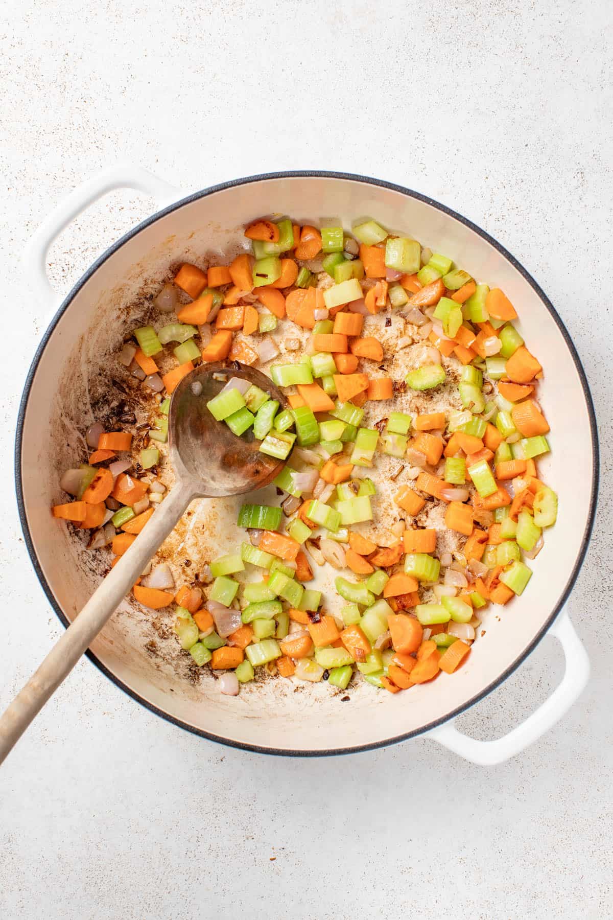 Cooking shallots, carrots, and celery in a skillet.