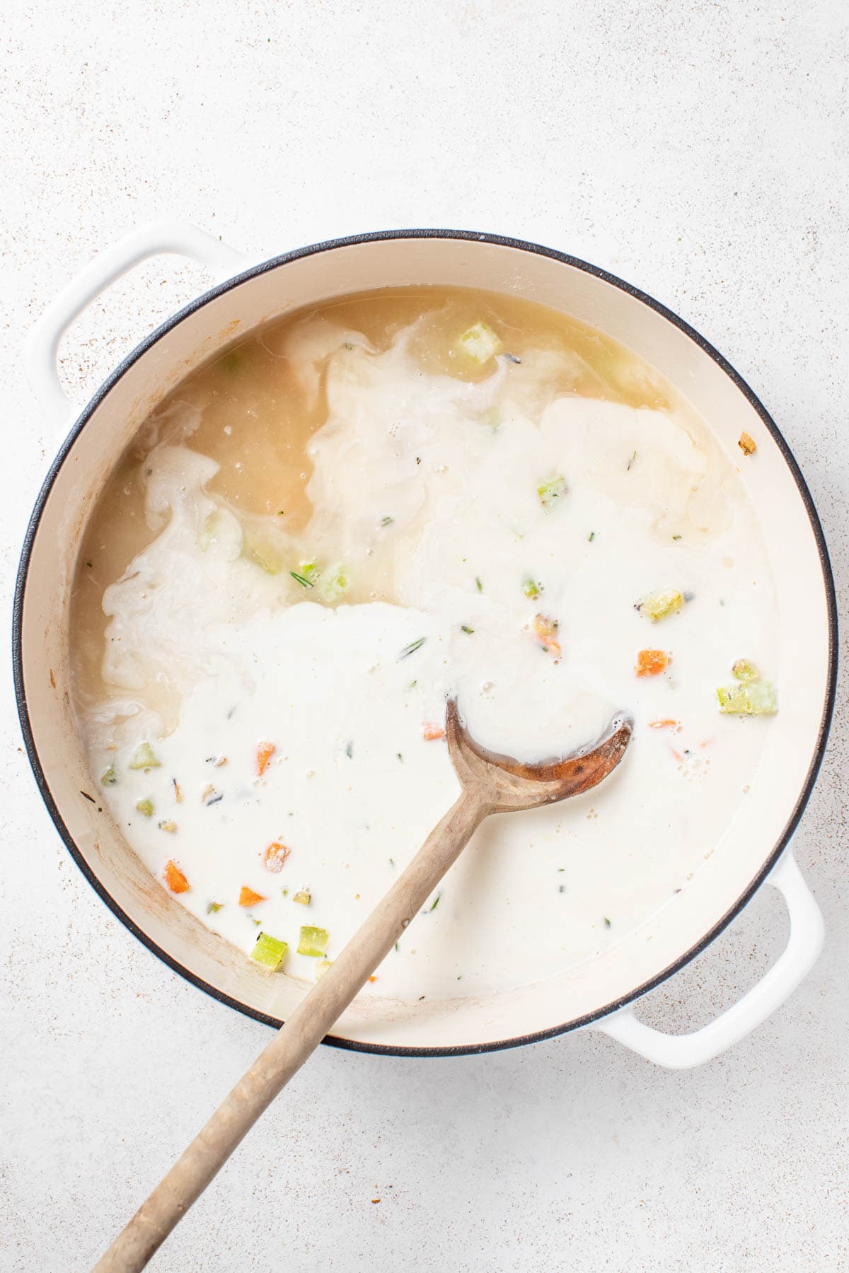 Adding in broth and heavy cream to the skillet.