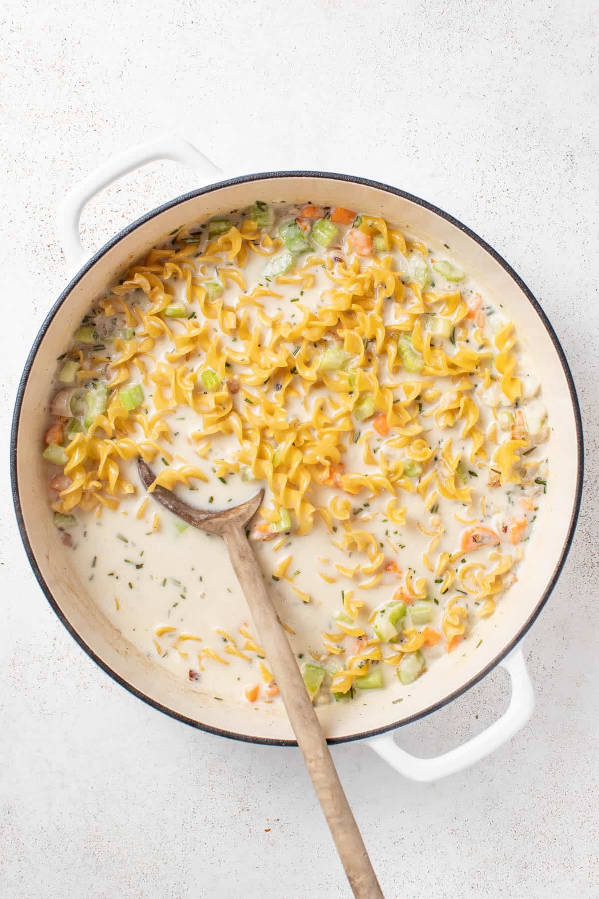 Stirring in egg noodles to the broth and cream.