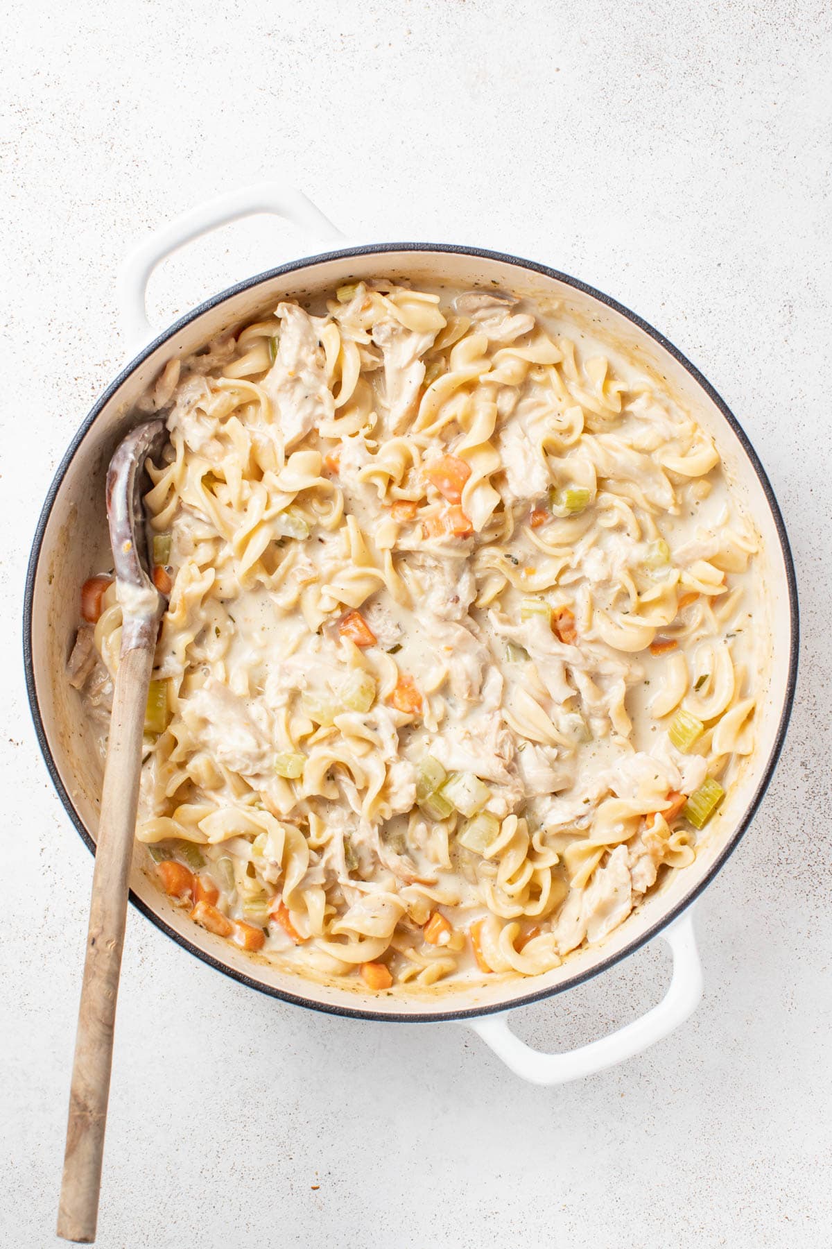 Adding rotisserie chicken to the noodle skillet.