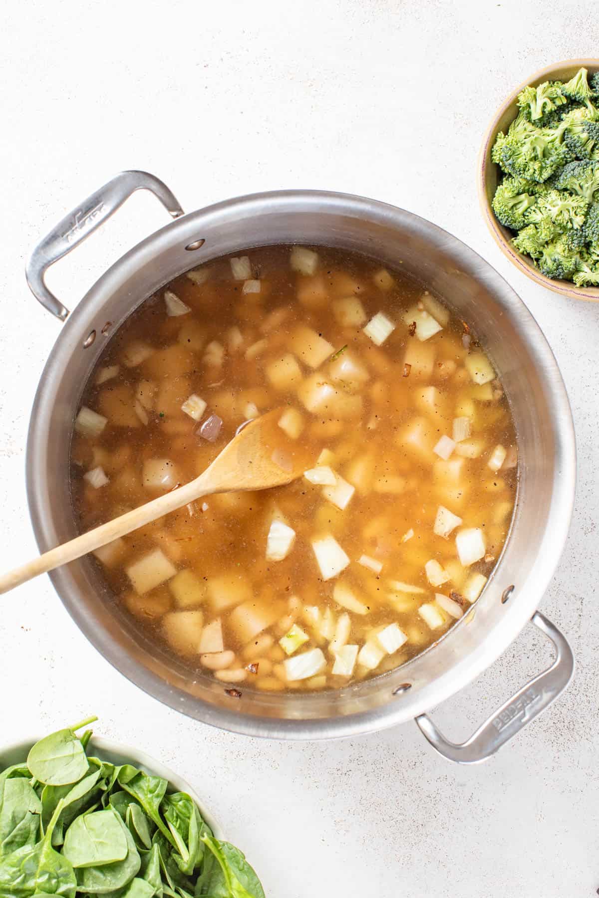 Adding broth and potatoes to the soup.