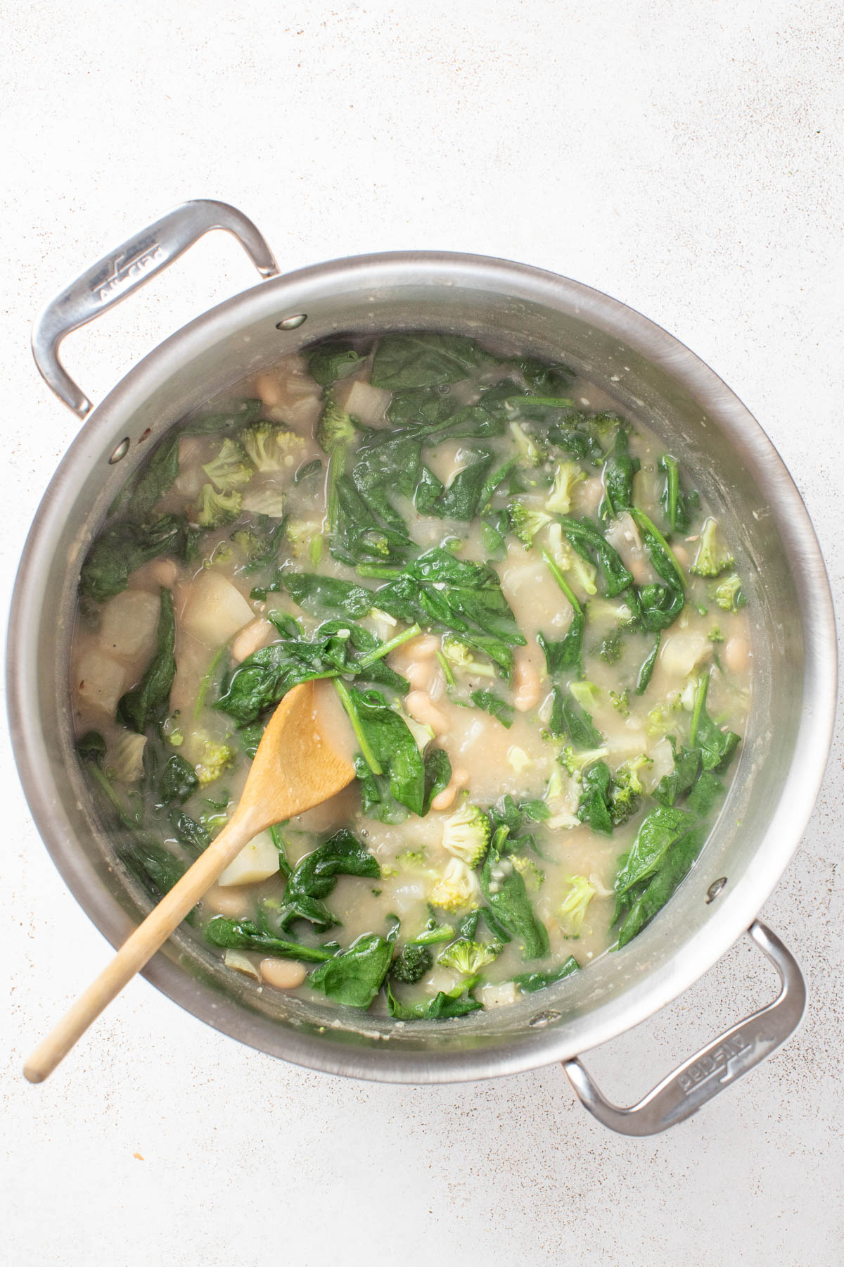 Stirring spinach and broccoli into the soup.