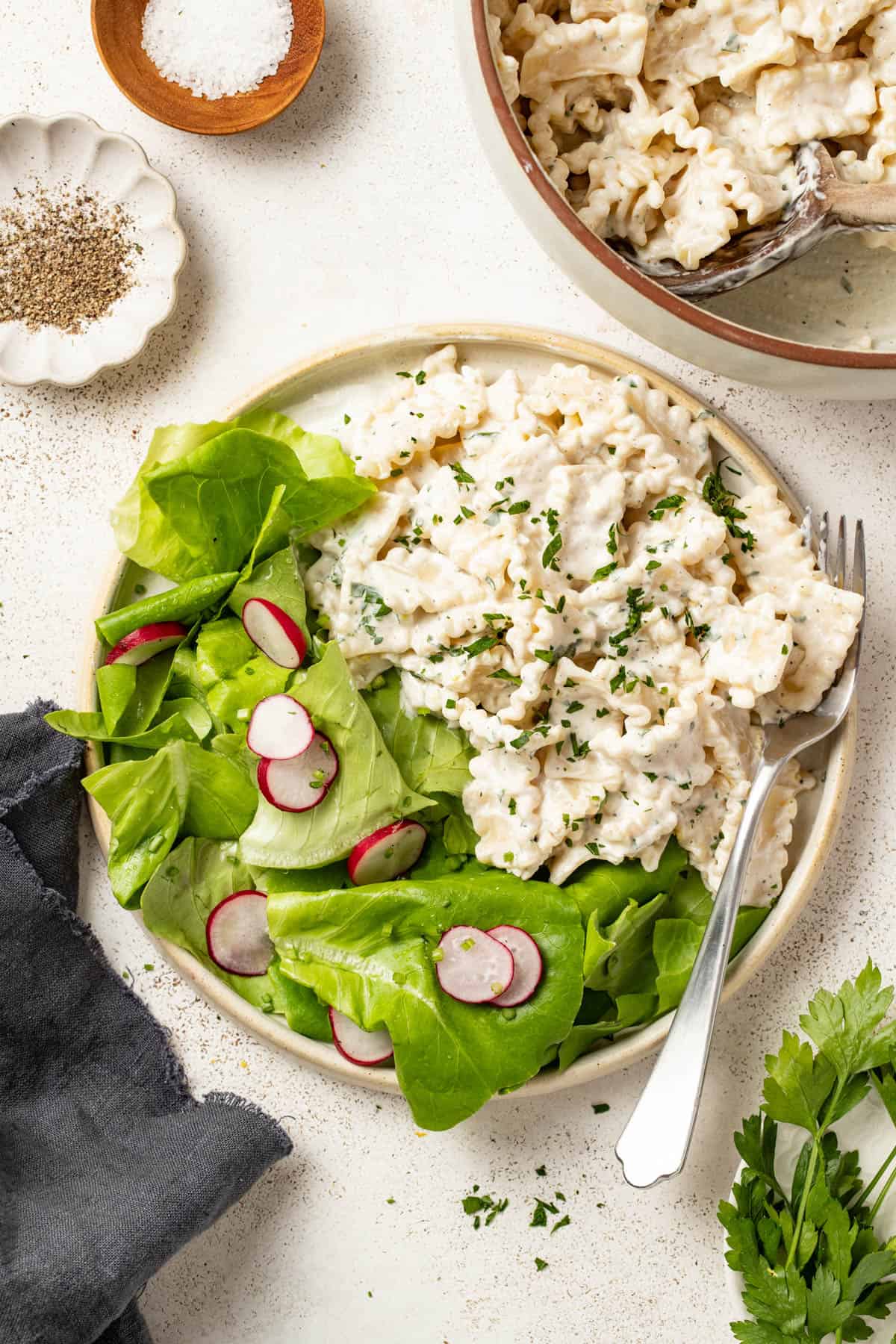 Pasta with cream cheese next to a simple green salad.