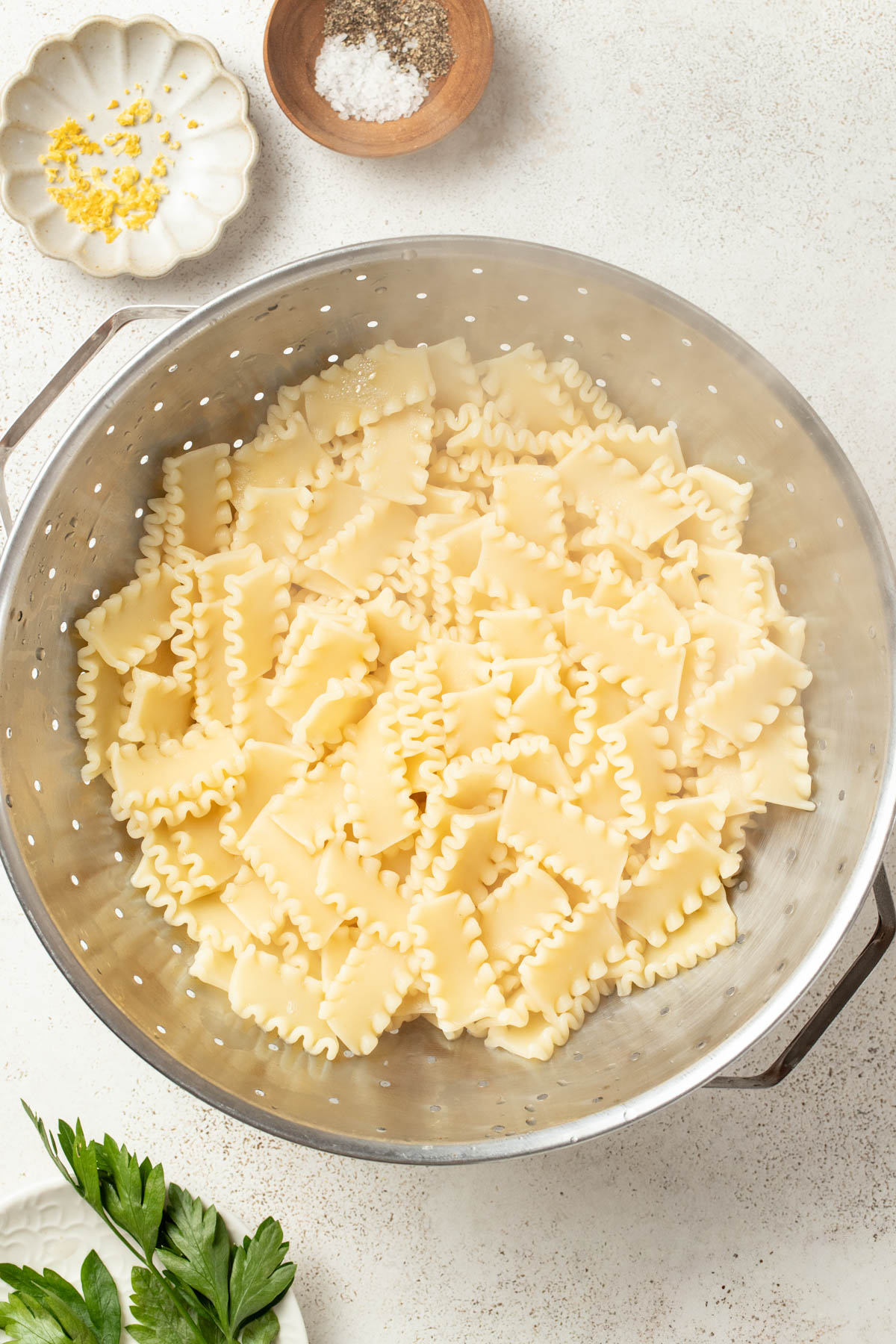 Draining the pasta and reserving the pasta water.