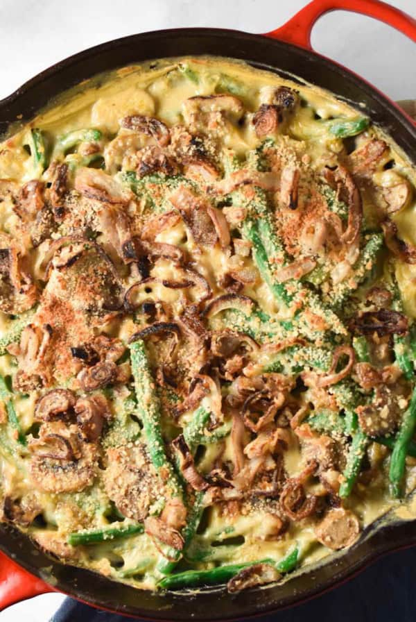 A cast iron skillet with green bean casserole made with fresh green beans and crispy shallots on top.