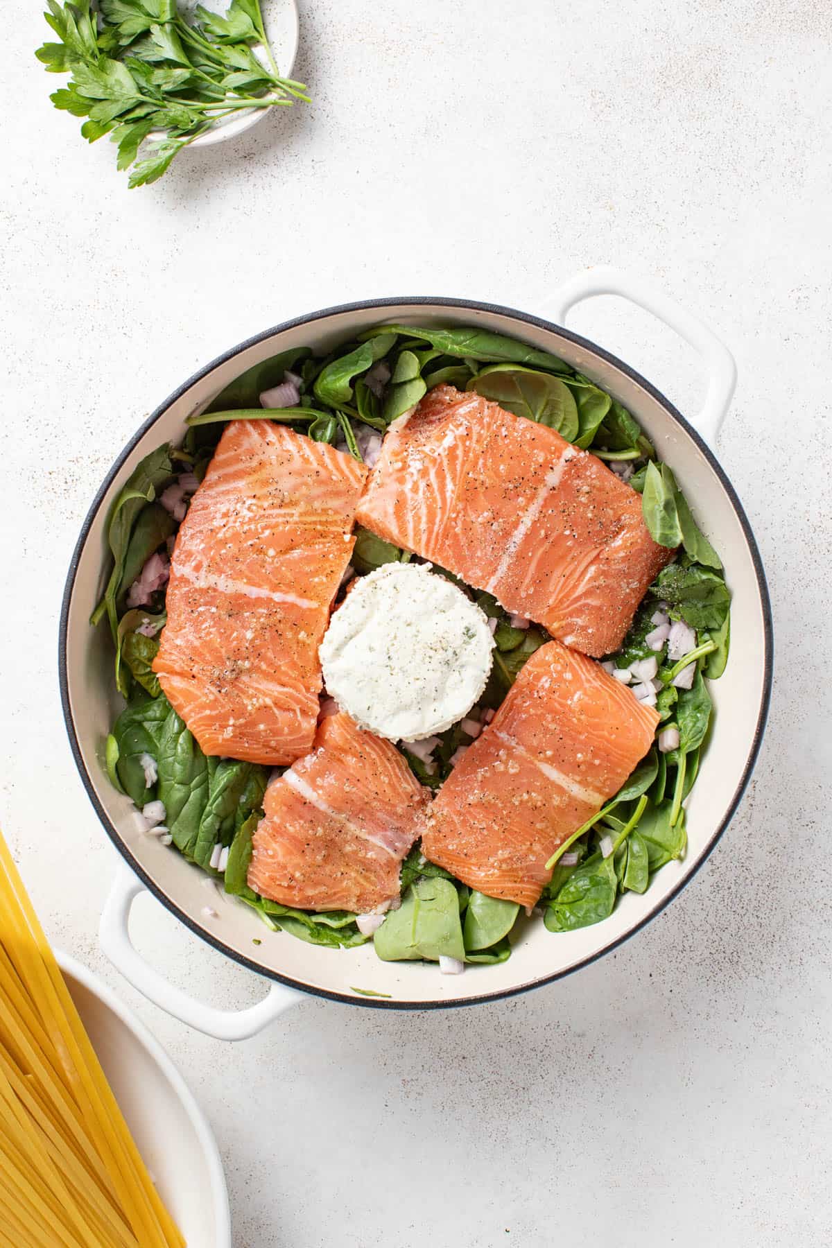Adding salmon to the pan with the boursin cheese and spinach.