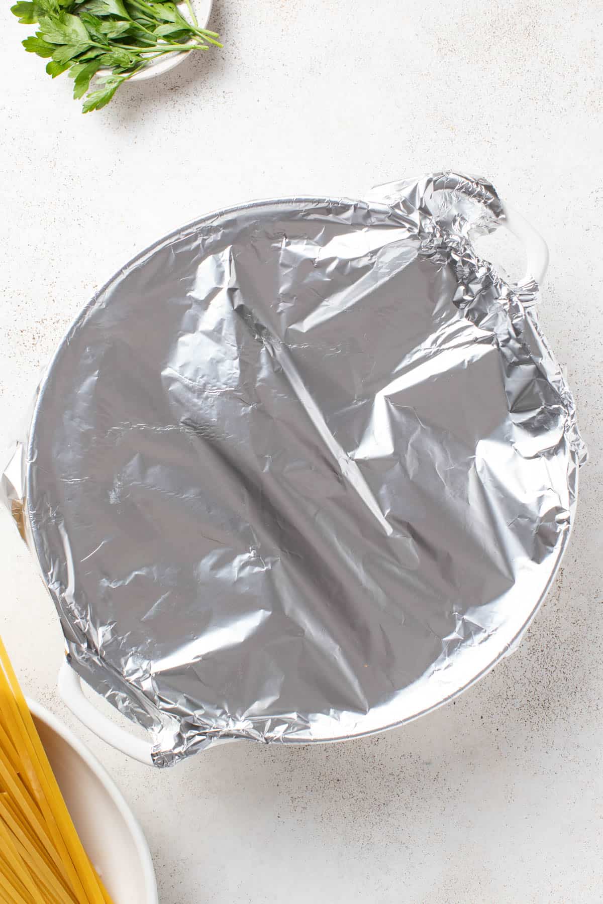 Covering the pasta pot with tin foil for baking.