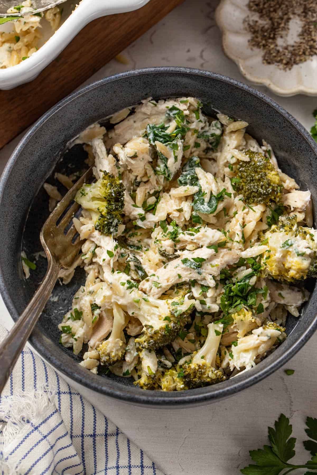 Chicken and orzo with broccoli and spinach in a bowl.