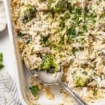 A spoon scooping into a creamy chicken orzo bake with Boursin cheese.