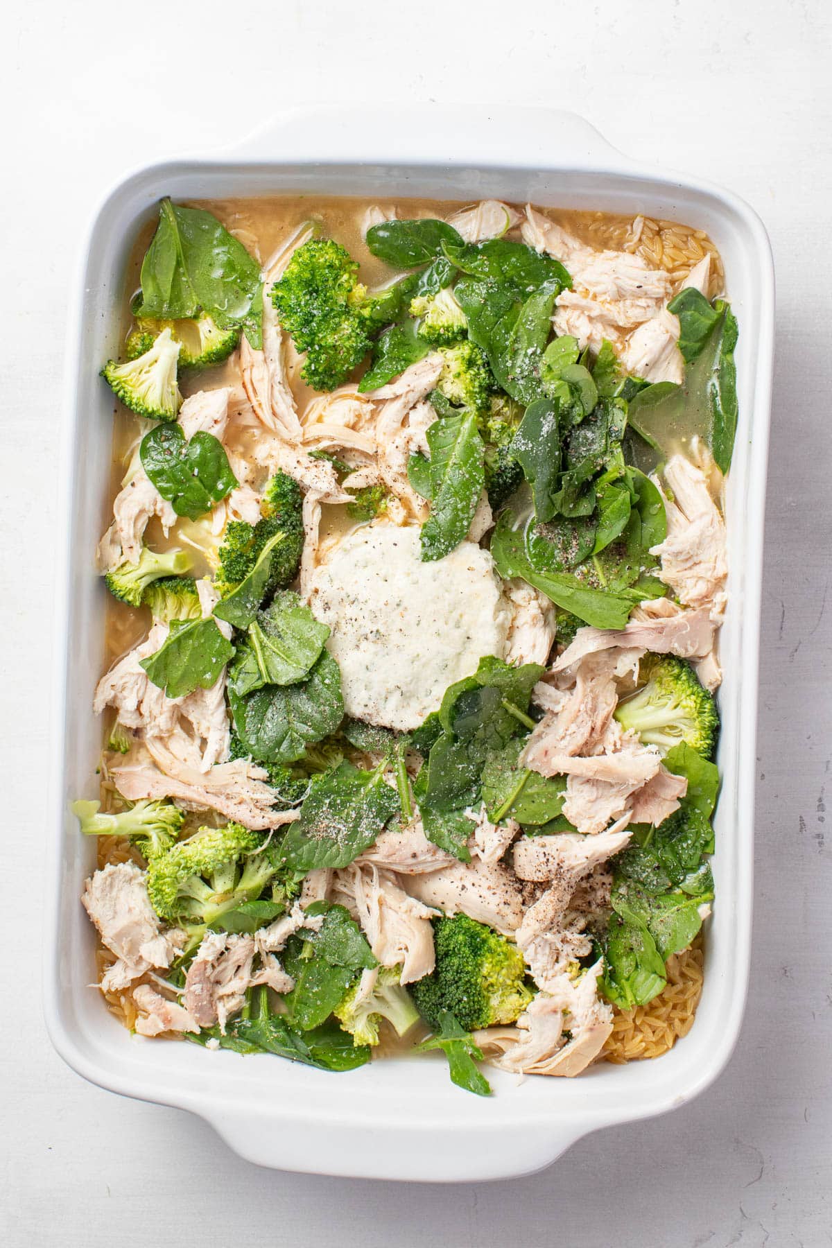 Adding broth to the chicken, orzo, and Boursin cheese.