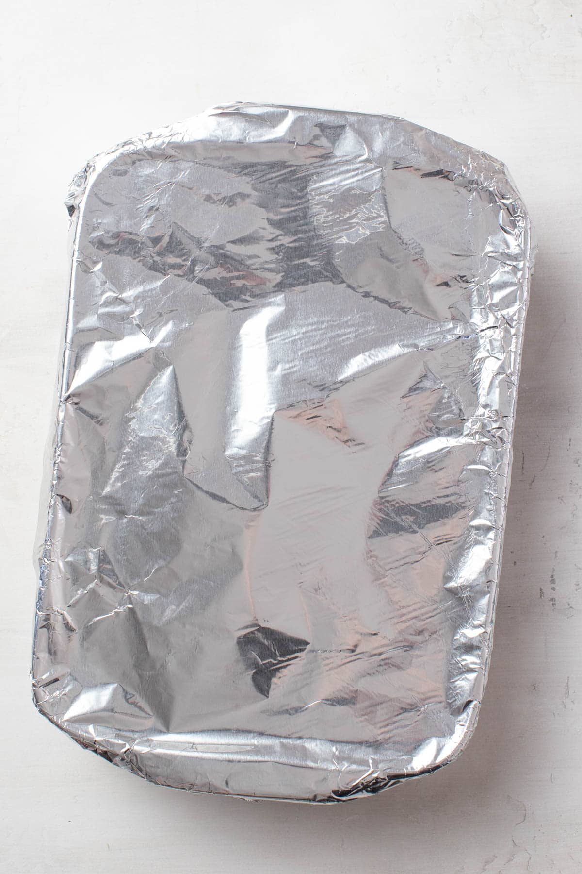 Covering the baking dish with tin foil.