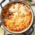 A spoon scooping out a cheesy beef enchilada casserole.