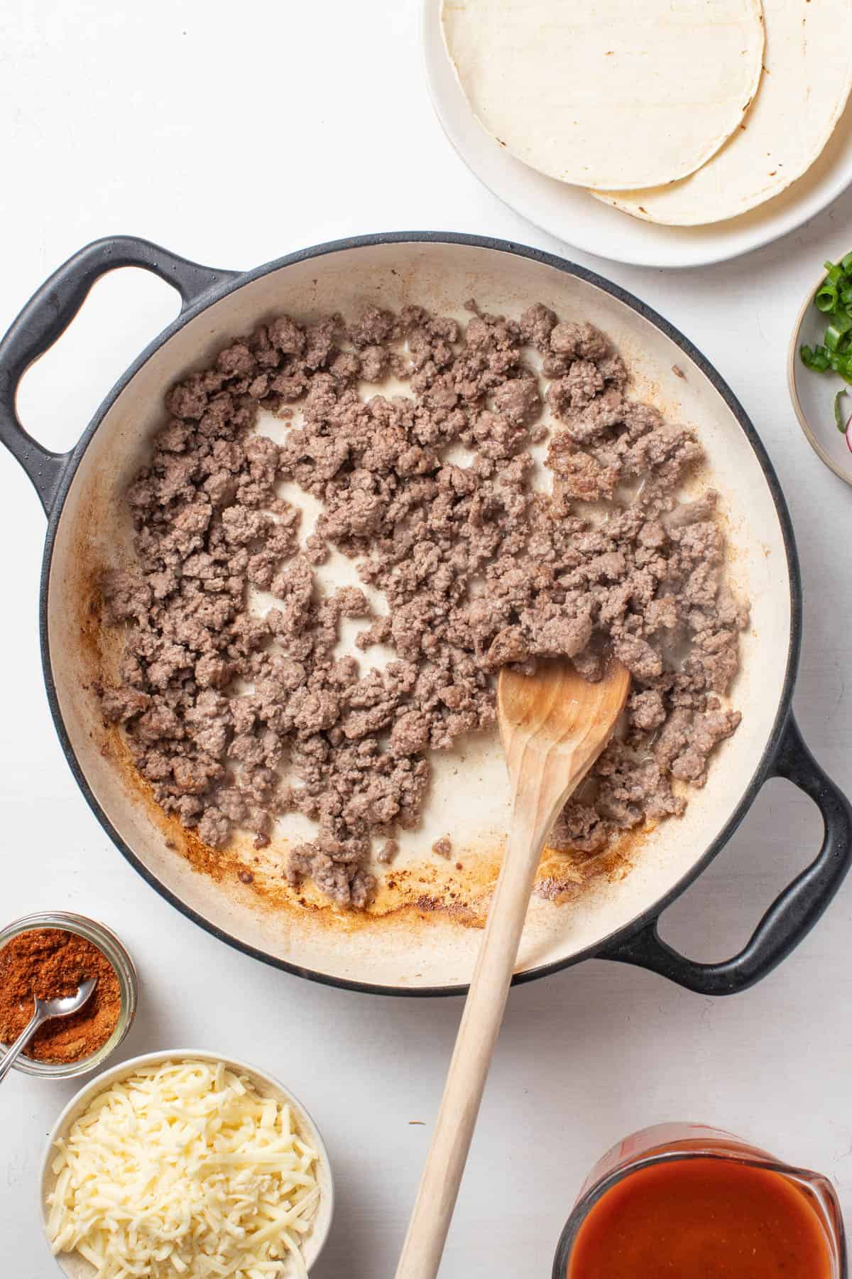 Browning ground beef in a cast iron pan.