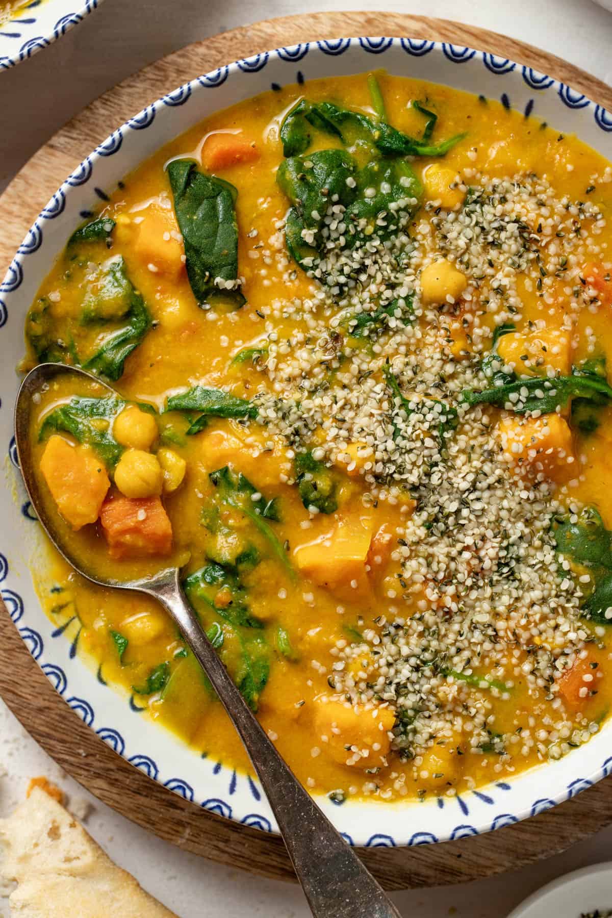 Sweet potato and chickpea stew with coconut milk and spinach in a bowl with a spoon.