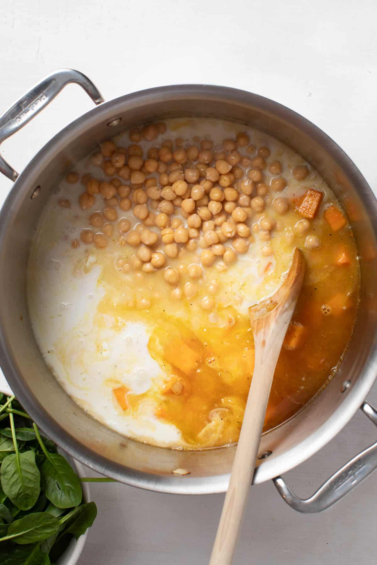 Adding coconut milk into the stew with chickpeas.