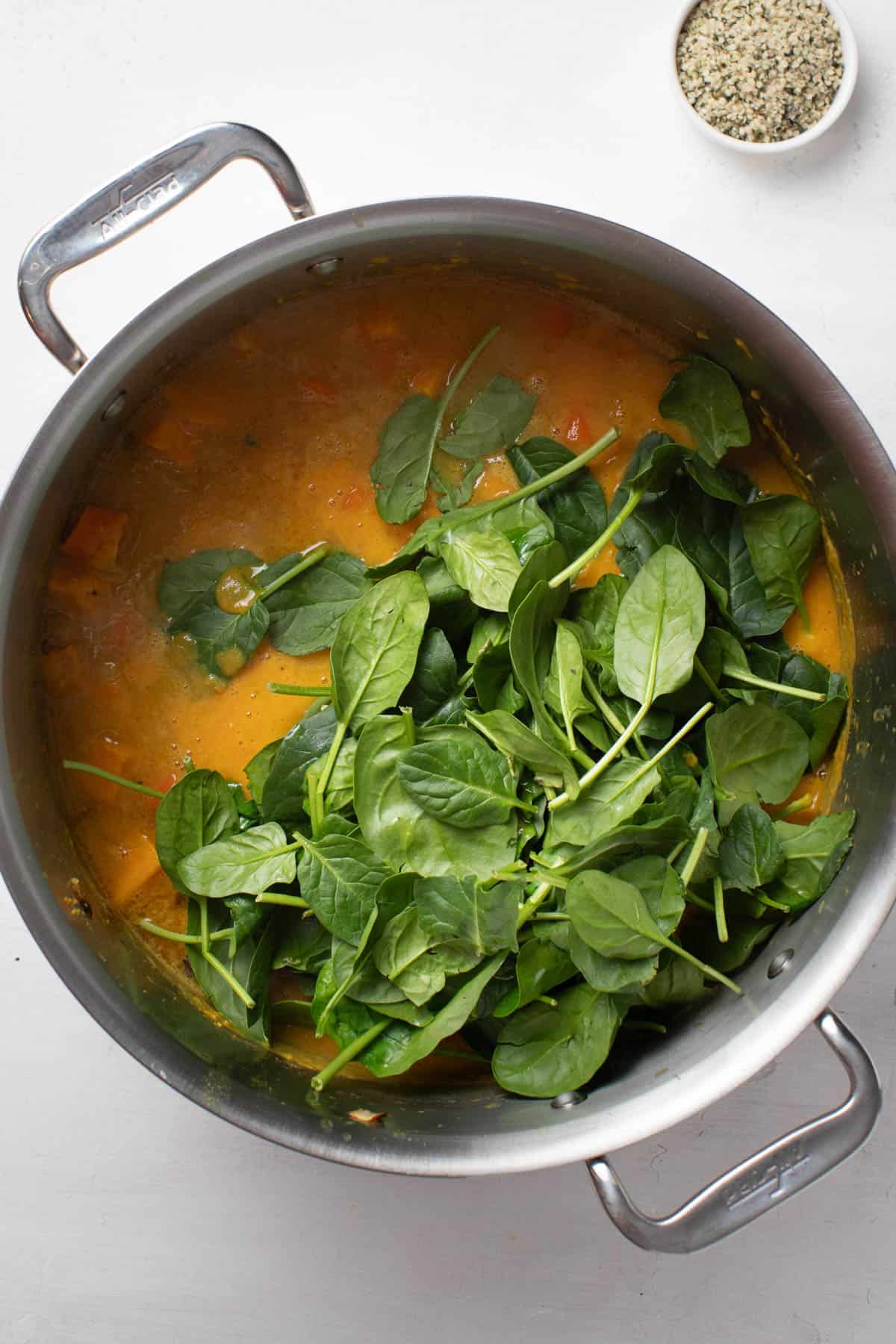 Adding fresh spinach leaves to the soup.