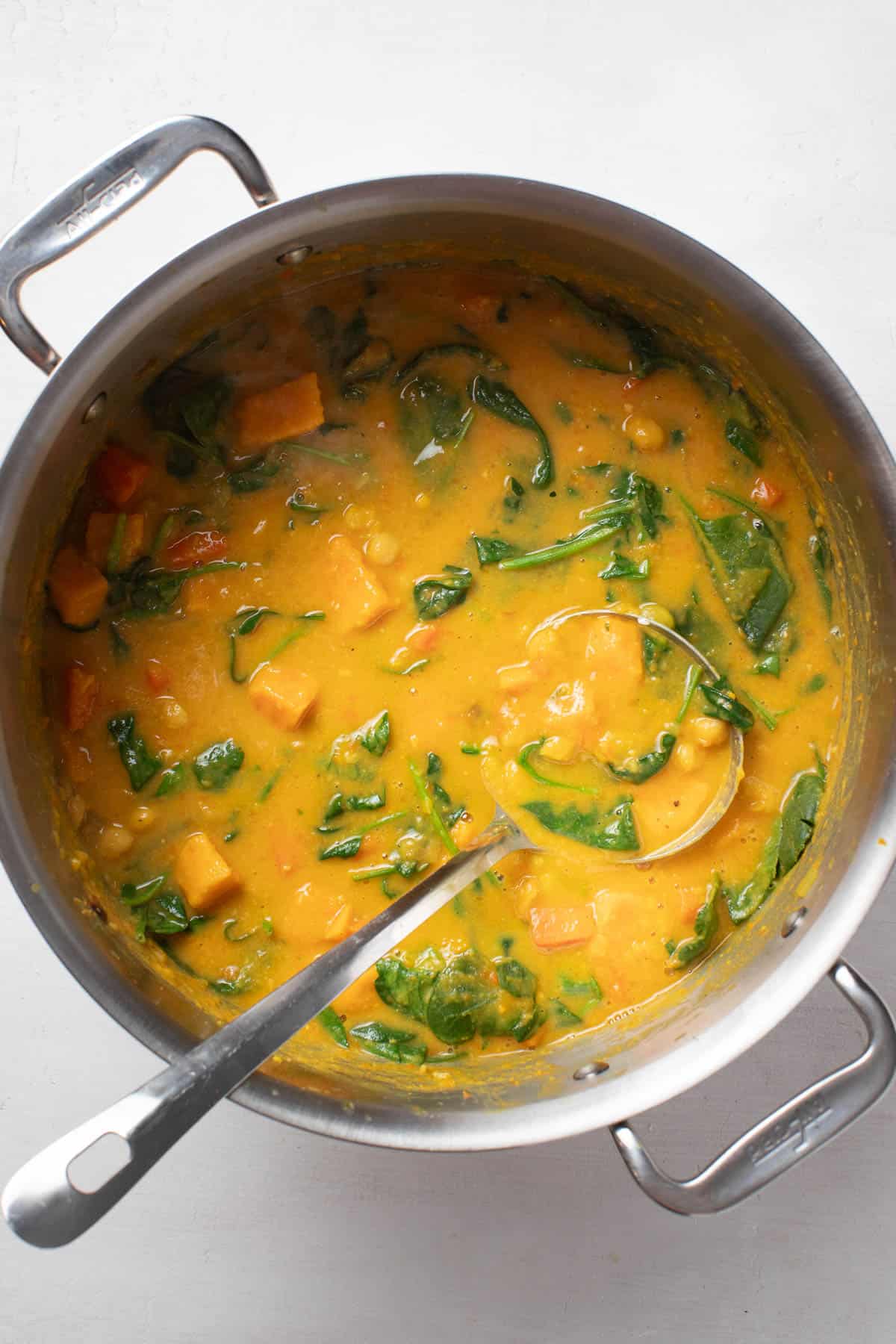 Stirring the cooked spinach into the chickpea stew.