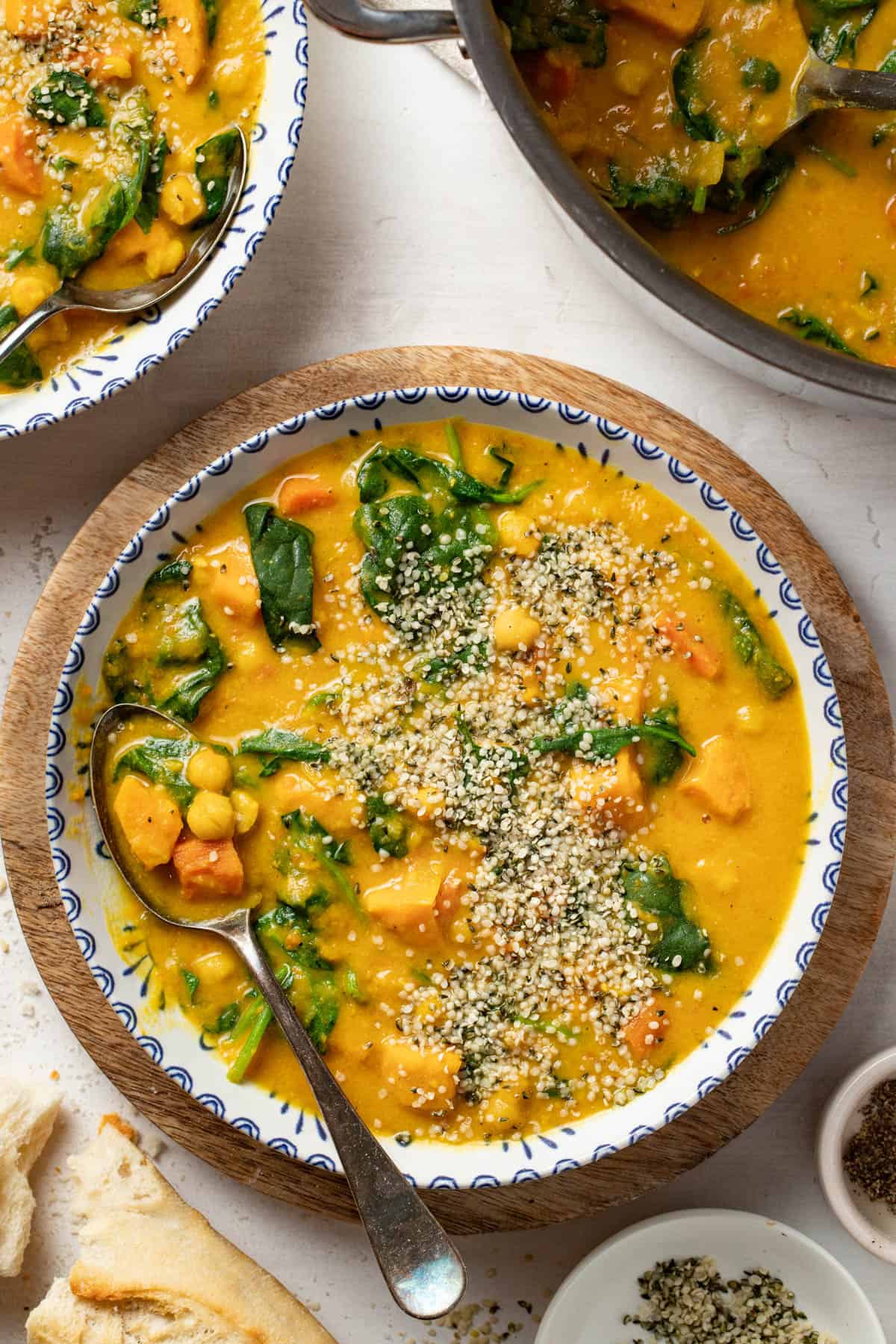 Chickpea stew with turmeric and ginger in a blue and white bowl on top of a cutting board.