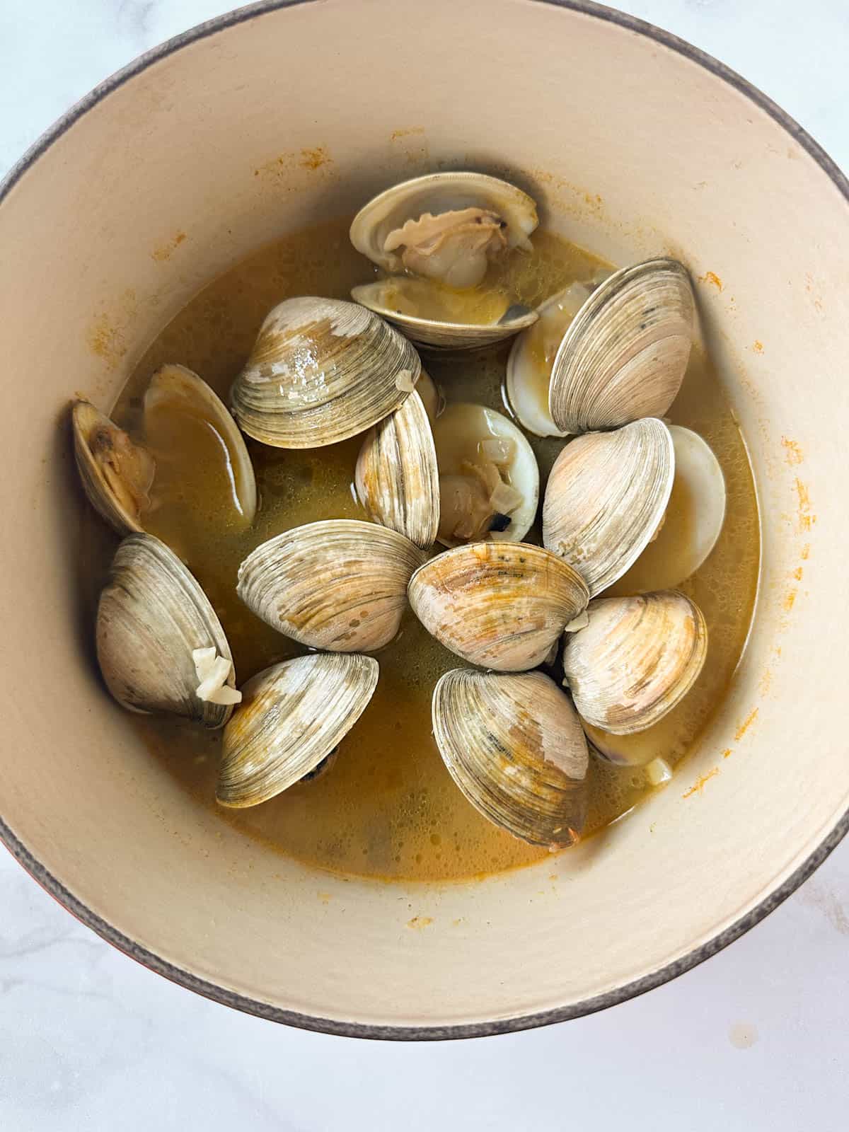 Open littleneck clams in a dutch oven in broth after cooking.