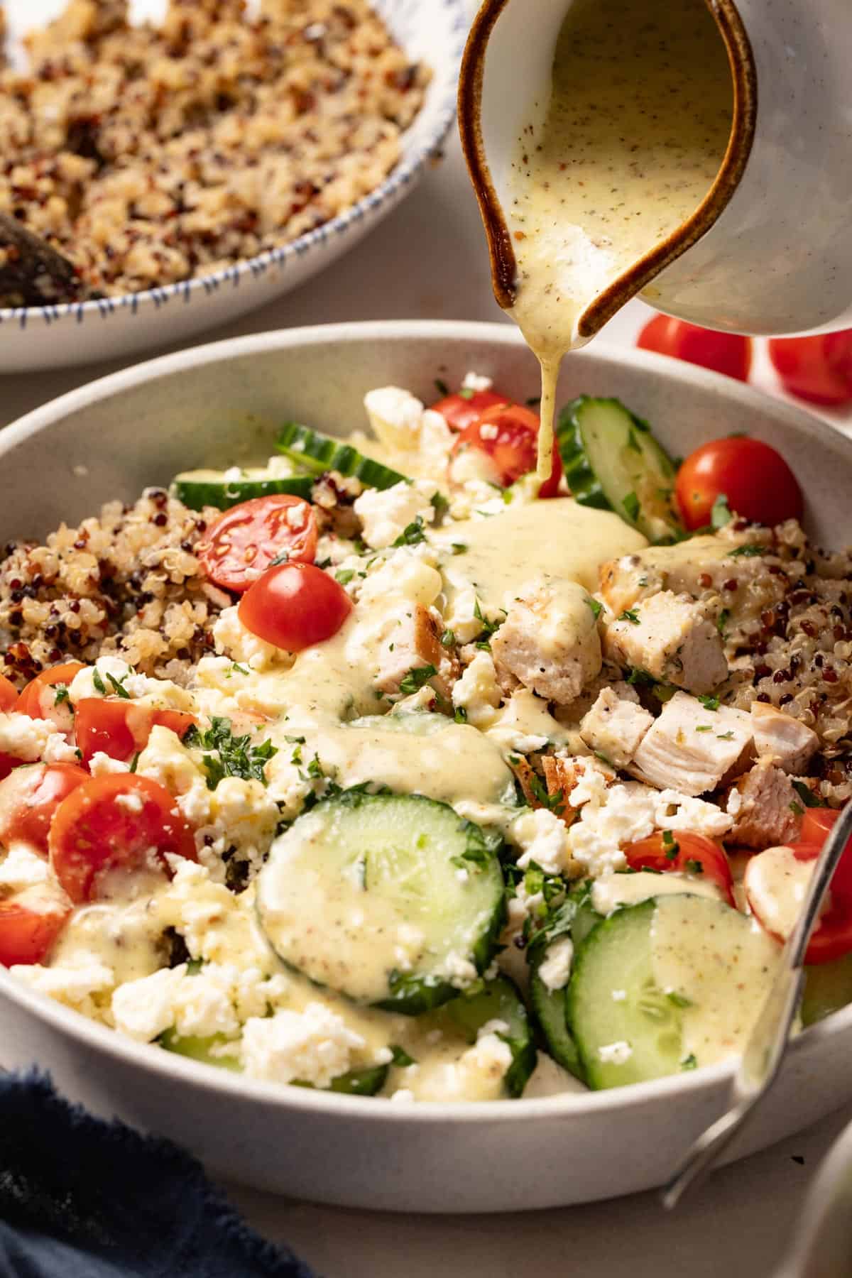 Pouring the Mediterranean vinaigrette on top of the chicken and quinoa.