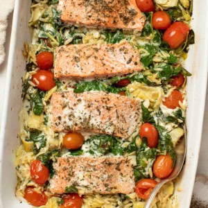 A Mediterranean salmon orzo bake in a white casserole dish.