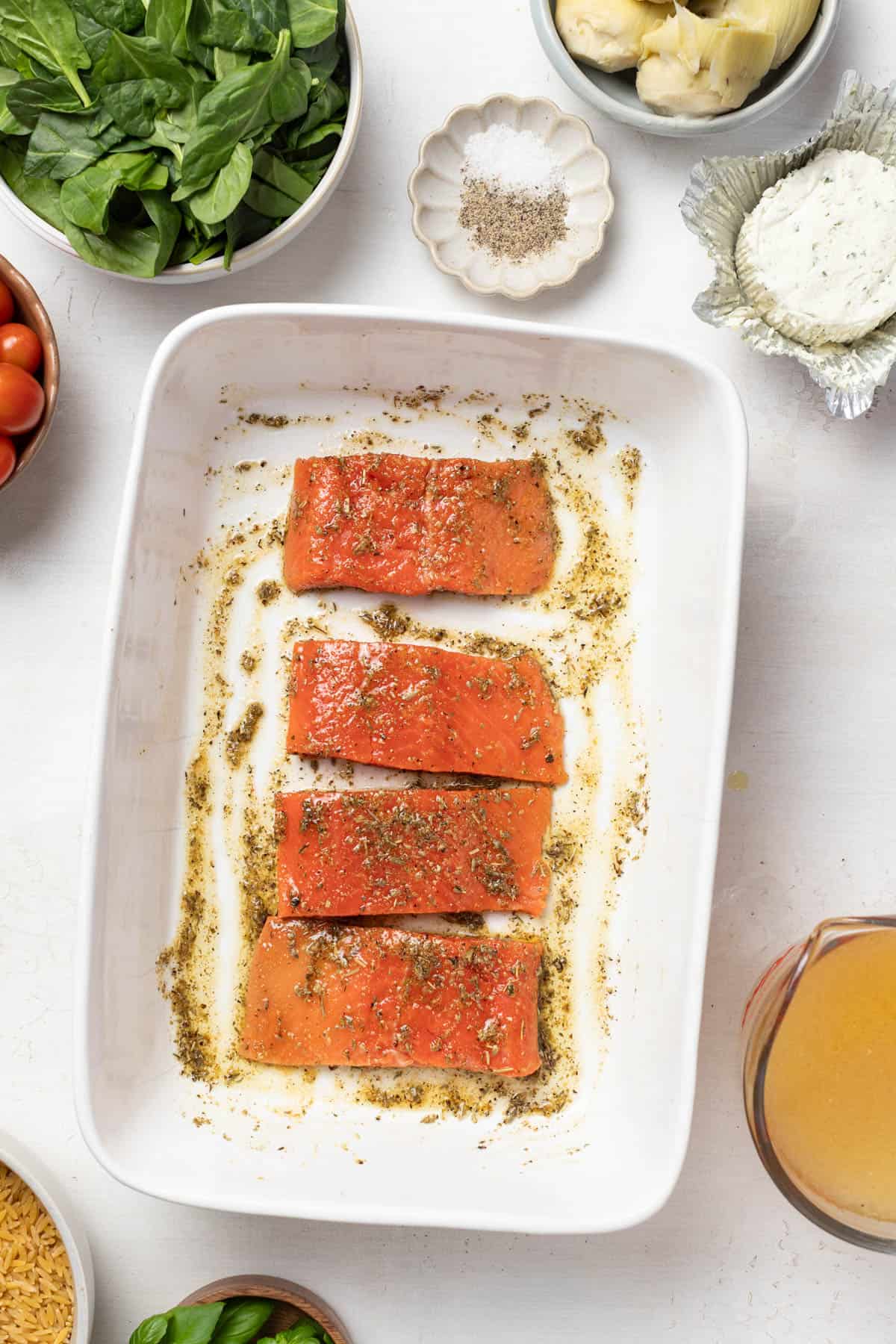 Salmon coated in spices and olive oil in a white baking dish.