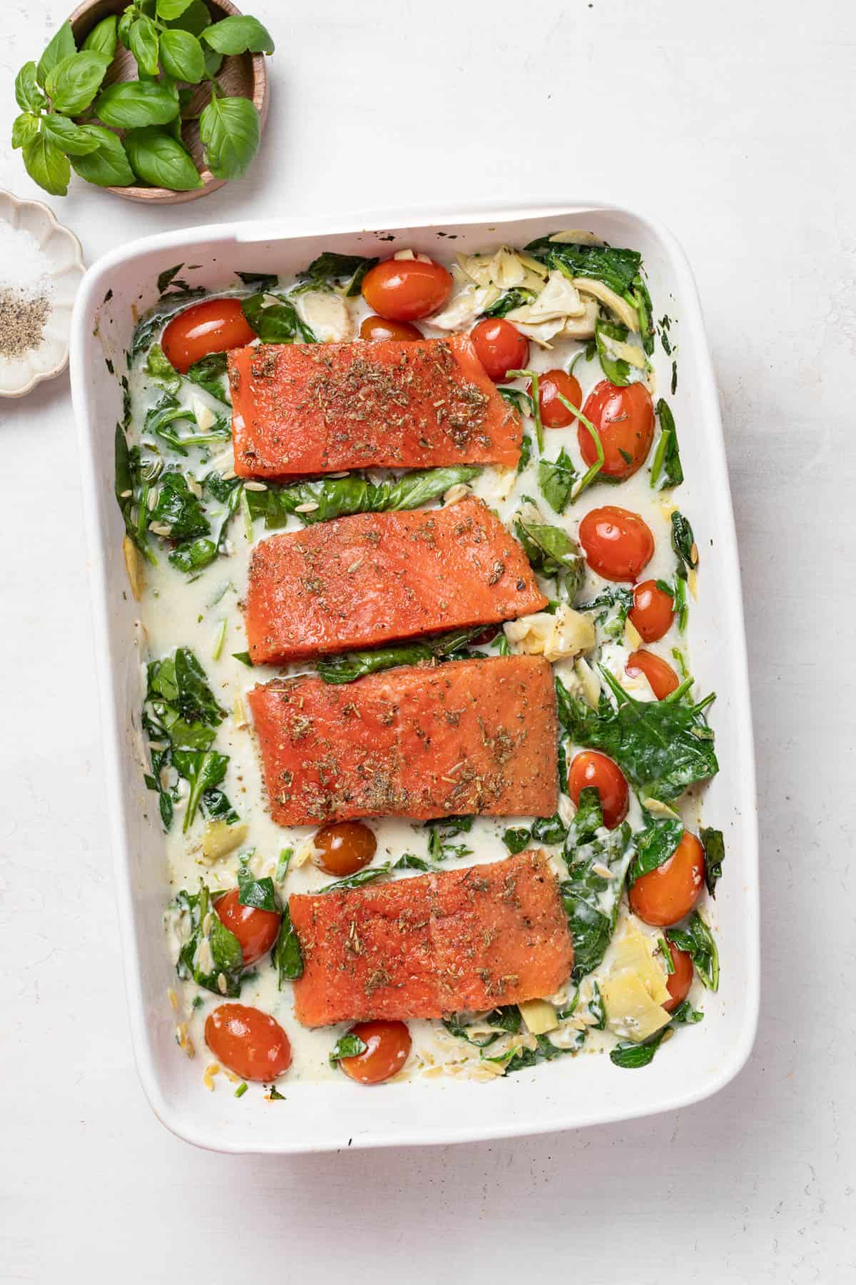 Adding the raw salmon fillets to the baking dish with the creamy orzo.