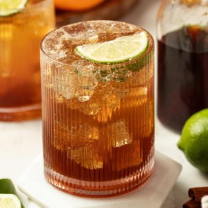 Homemade coke in a glass with ice, topped with a slice of lime.