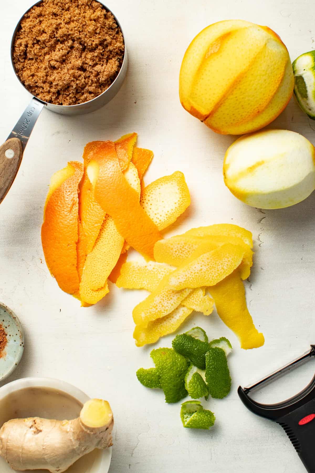 Peeling the oranges, limes, and lemons, with a peeler.