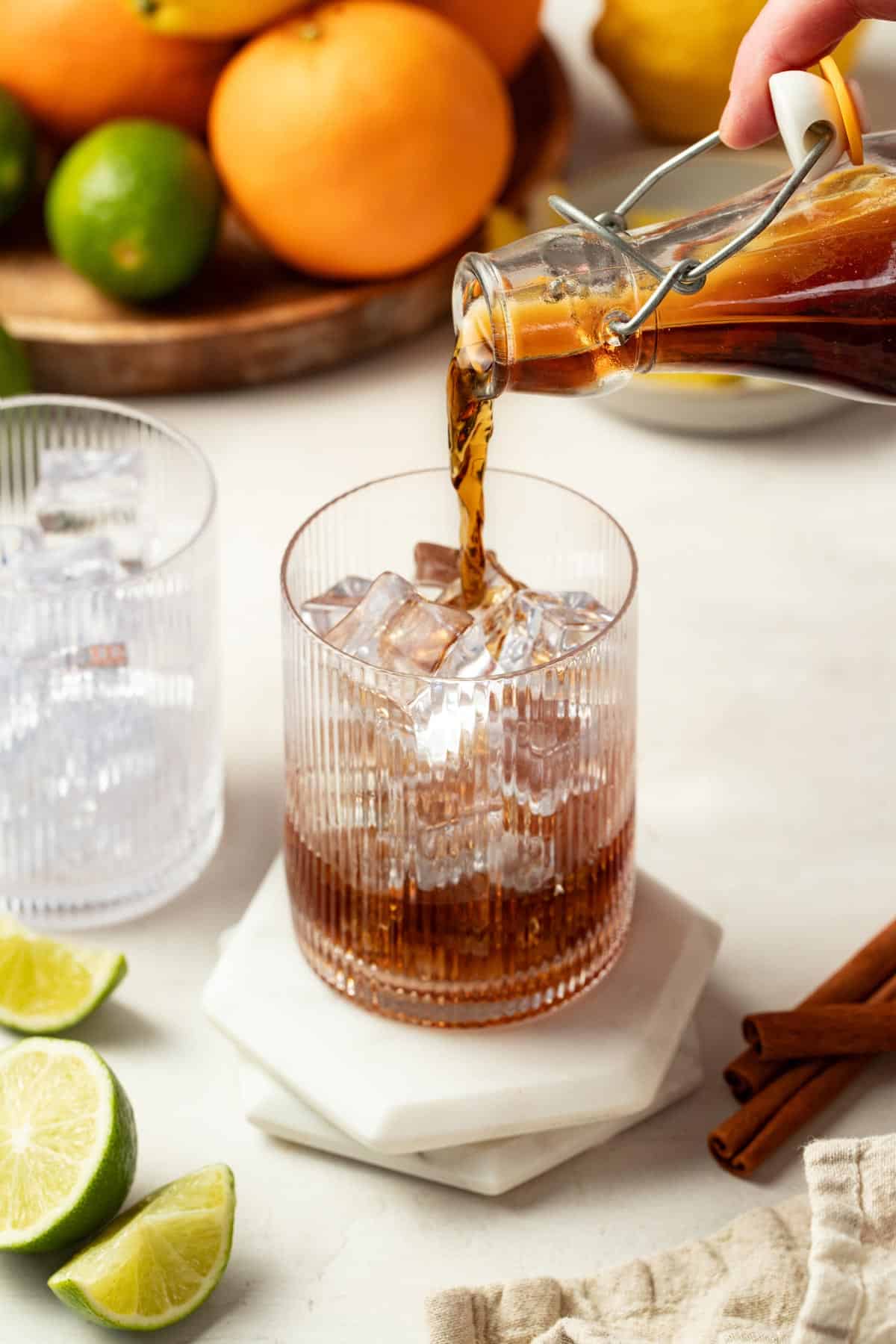 Pouring cola syrup into a glass with ice cubes.