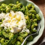 A pesto pasta with creamy burrata cheese melted on top.