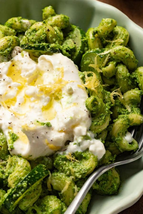 A pesto pasta with creamy burrata cheese melted on top.