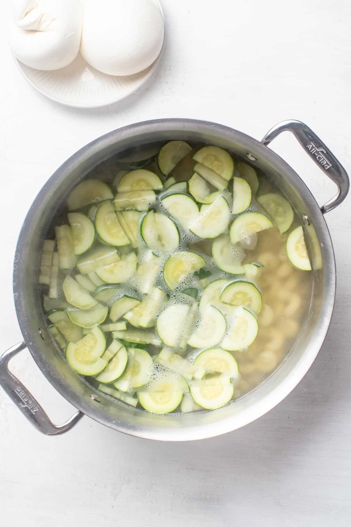 Boiling pasta and zucchini in a large pot.