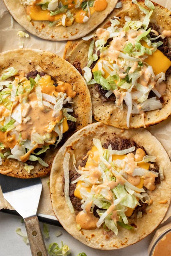A spatula scooping up a smash burger taco topped with big mac sauce.