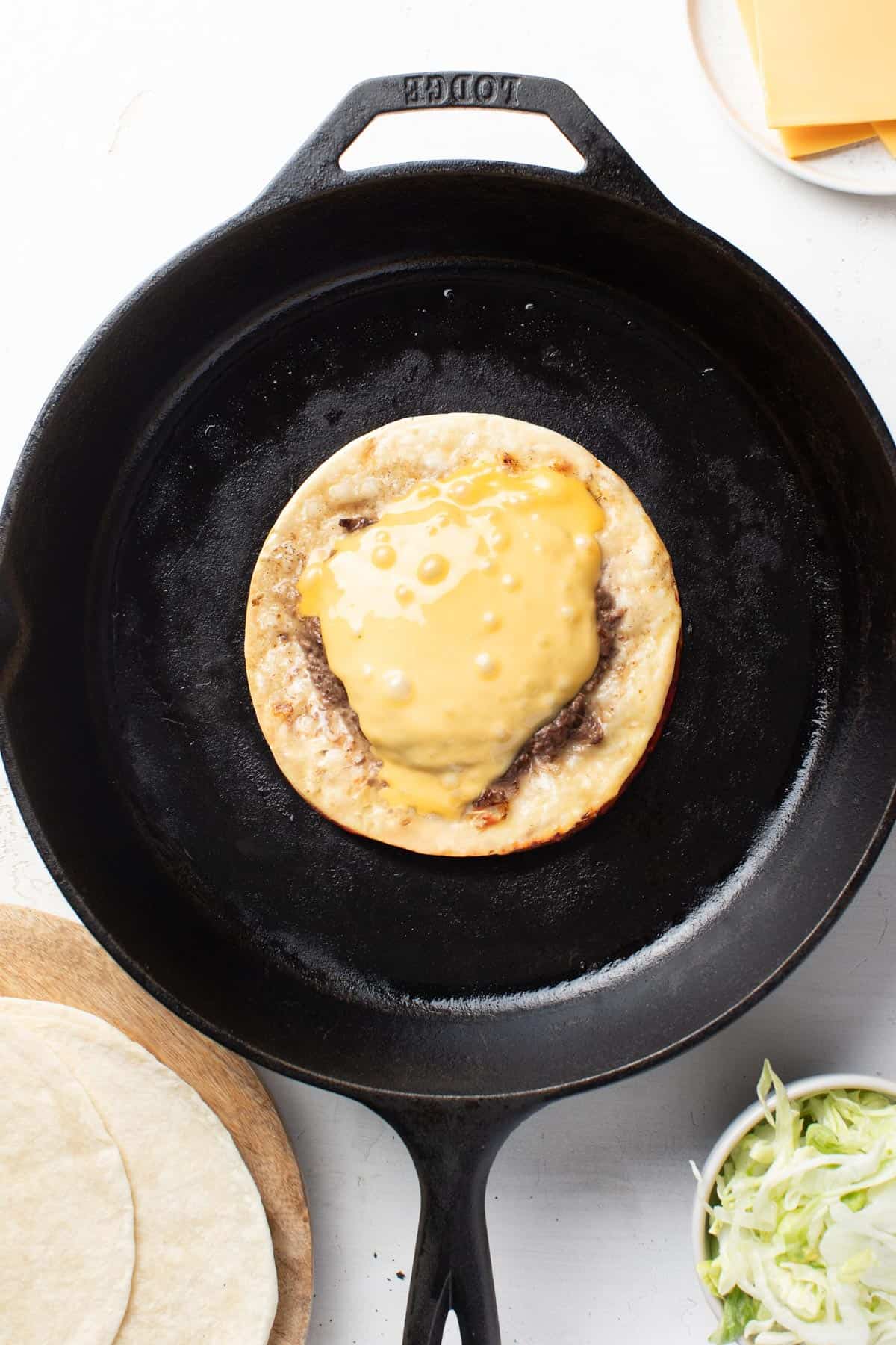 Cheese melted on top of the smash burger and tortilla.