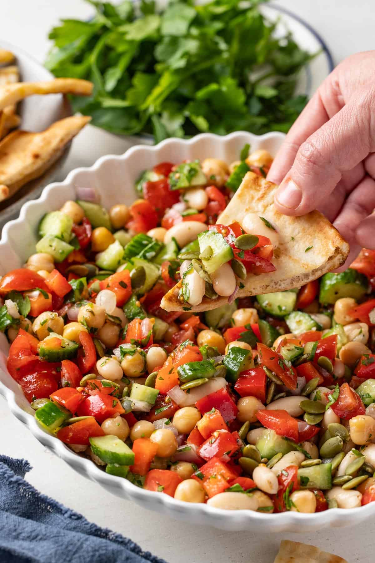 A pita being dipped into the white bean salad to show it as an appetizer.