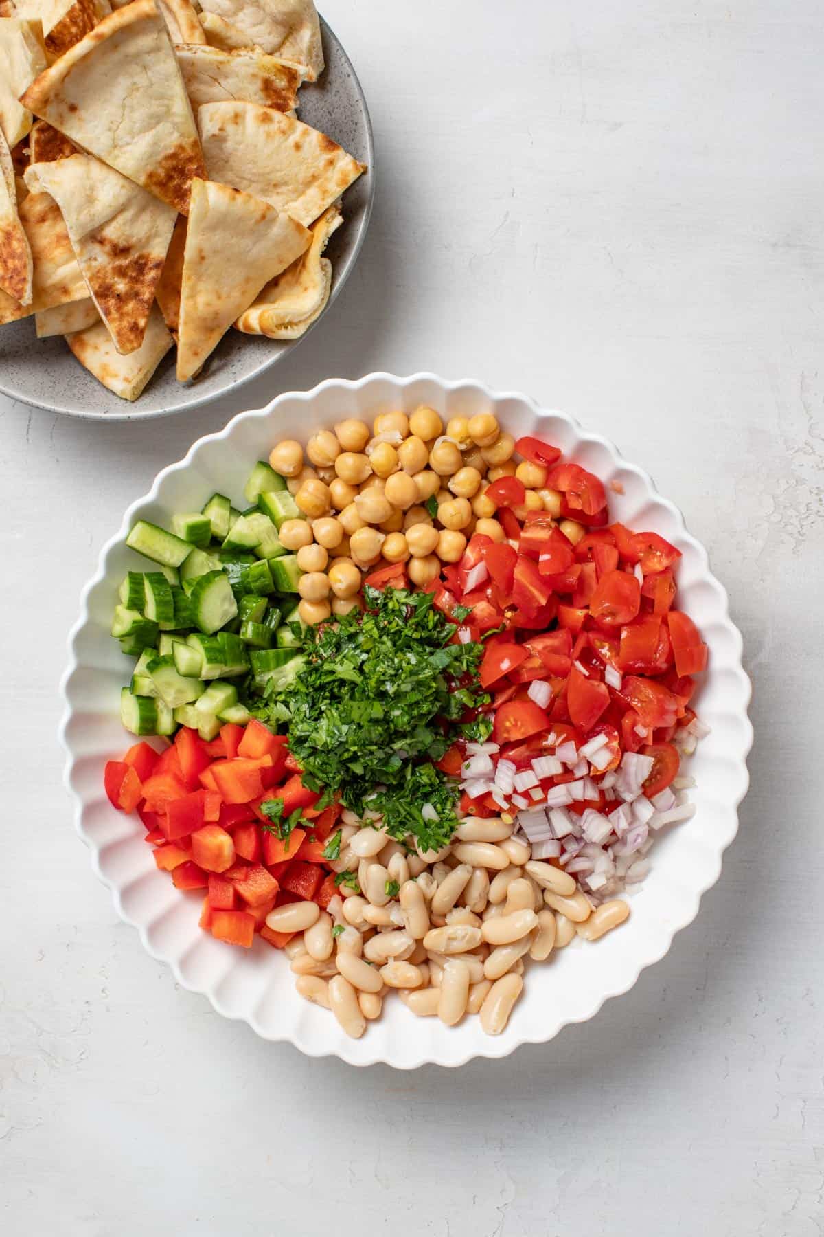 Ingredients for a dense bean salad separated in a mixing bowl.