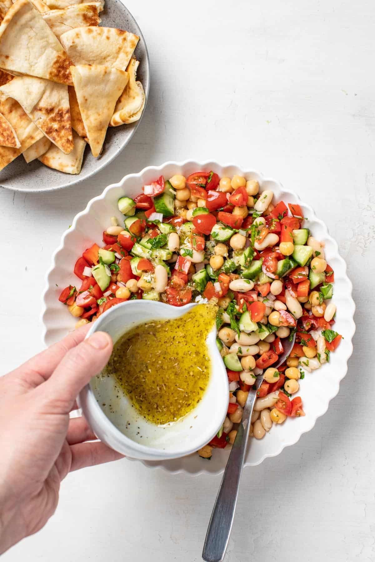 Pouring the Mediterranean vinaigrette into the bean salad.