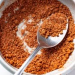 A spoon scooping into a bowl with a dry rub for ribs.
