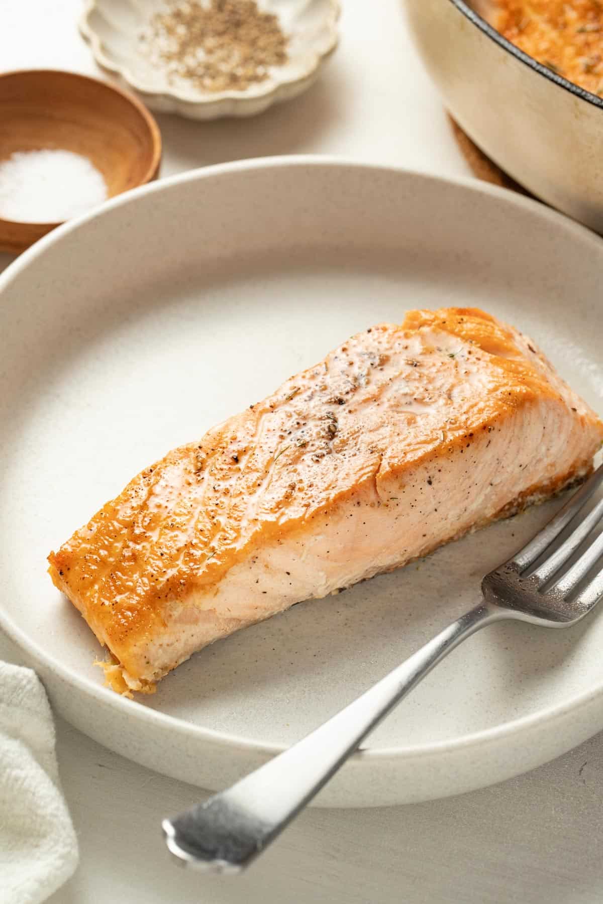 A crispy, golden brown seared salmon on top of a plate.