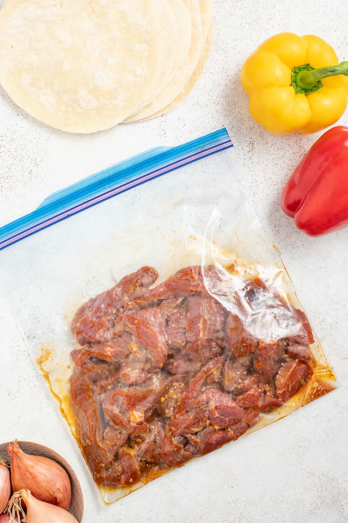 Flank steak marinating in a ziplock bag with spices, oil, and juice.