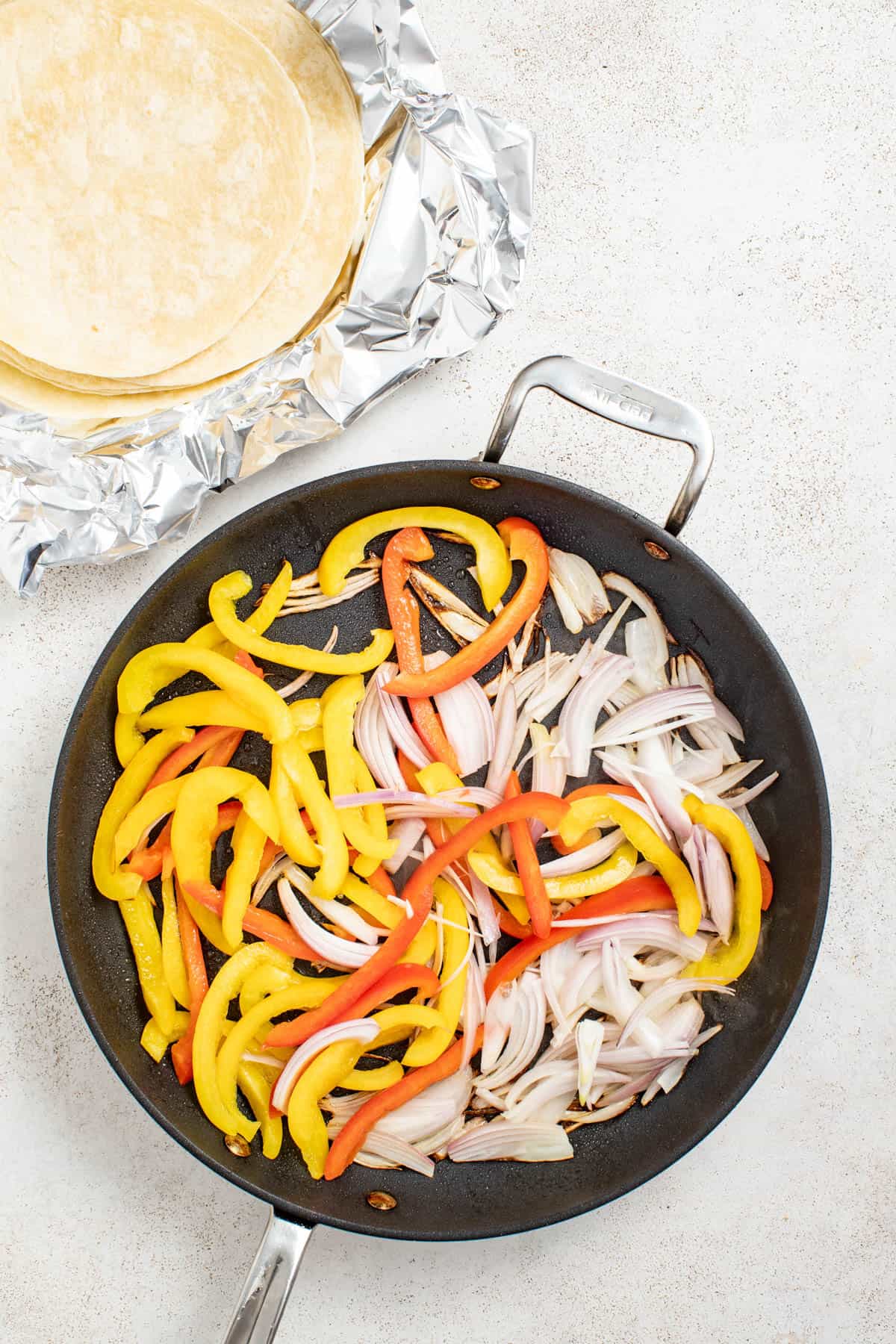 Searing peppers and onions in a cast iron pan.