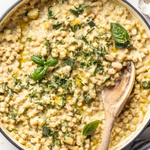 A large skillet with ditalini pasta in a creamy zucchini sauce that is topped with fresh herbs and lemon zest.