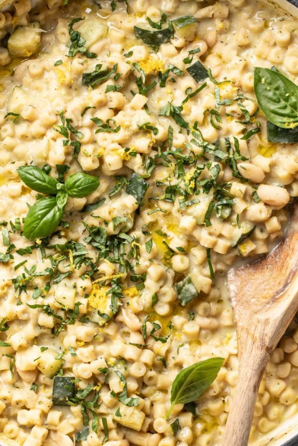 A large skillet with ditalini pasta in a creamy zucchini sauce that is topped with fresh herbs and lemon zest.