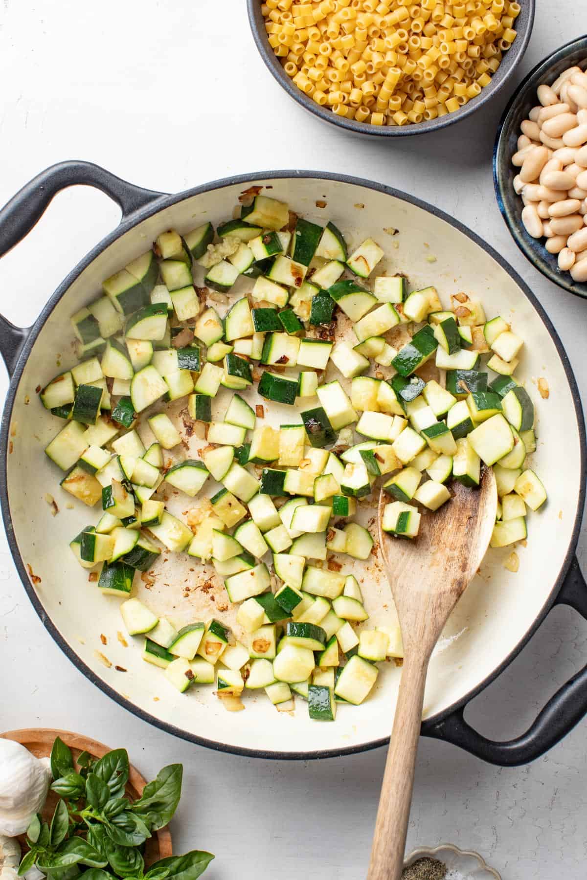 Browning the chopped zucchini and garlic in a large enameled cast iron pan.