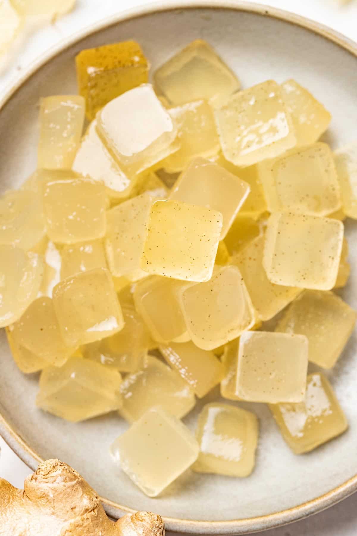 Homemade gummies in a bowl next to fresh ginger root.